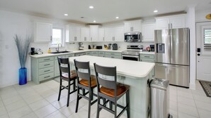 A modern kitchen with white cabinets, a stainless steel refrigerator, and a central island with bar stools. - Lakefront Hot Springs Condo w/ Dock Access & Views (Hot Springs)