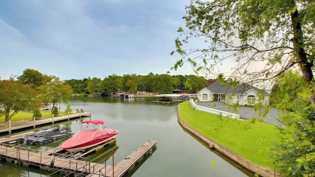 A lakeside dock with boats, a grassy area, and a house with a white exterior. - Lakefront Hot Springs Condo w/ Dock Access & Views (Hot Springs)