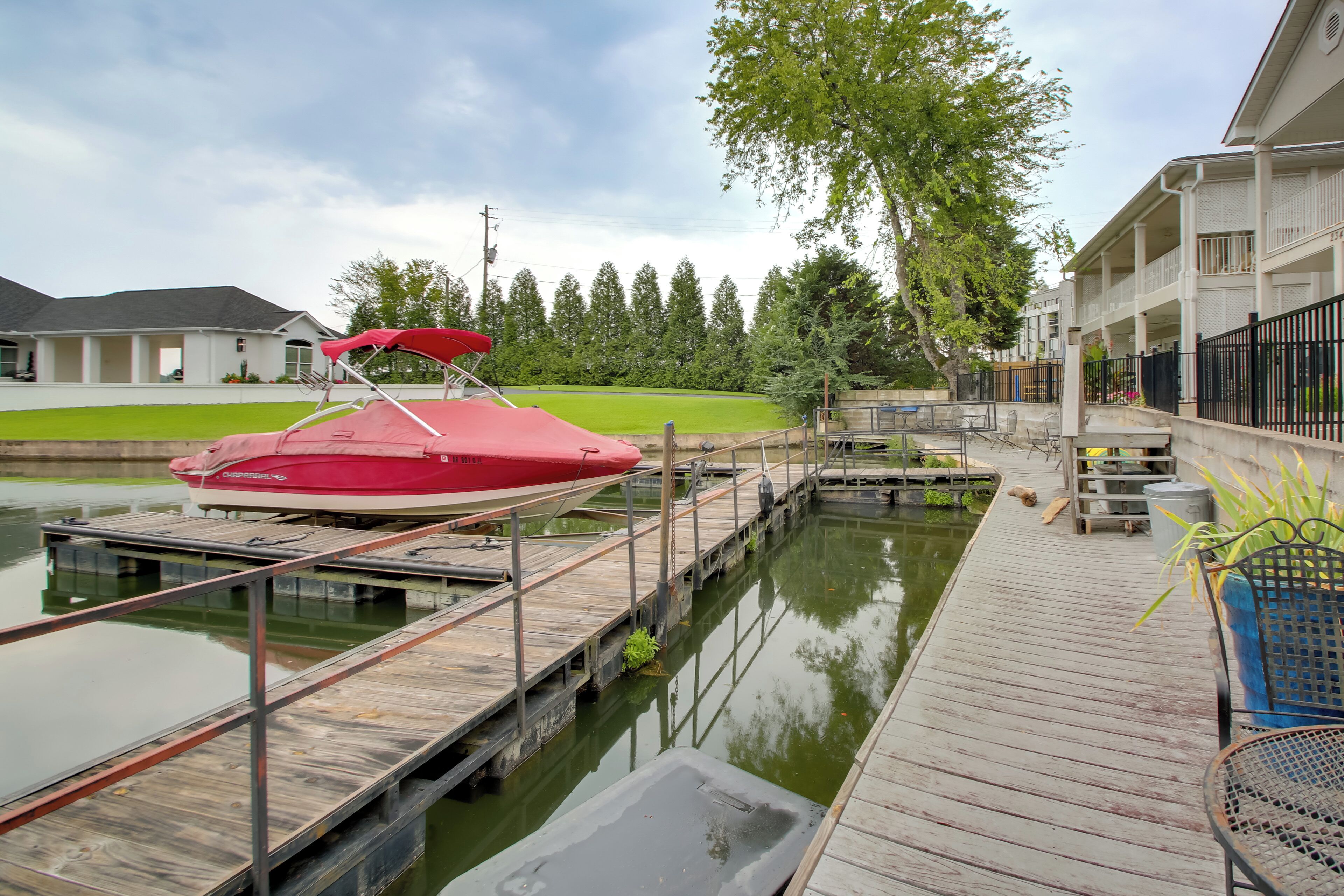 Un quai avec un bateau rouge, une passerelle en bois et un bâtiment doté d’un balcon.