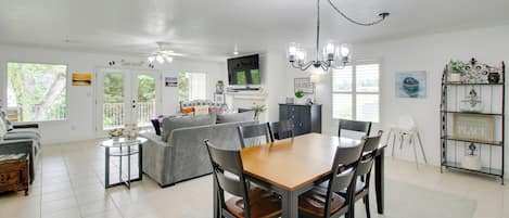 Un salón amplio con comedor, cocina y televisor montado en la pared.