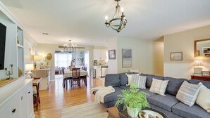 A spacious living room with a grey sofa, wooden coffee table, and a dining area with a table and chairs.