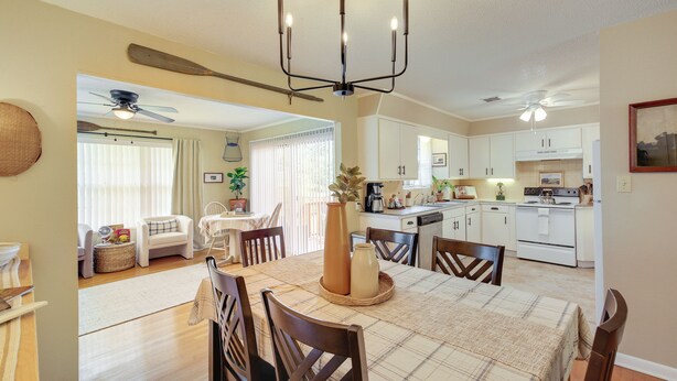 A dining area with a table set for four, a chandelier, and a view into the kitchen.
