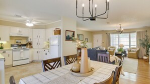 A spacious living area with a dining table, chairs, a sofa, and a kitchen area with cabinets and appliances.