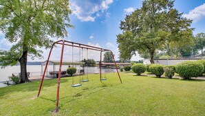 A grassy area with a swing set and a lake in the background. - Cozy Hot Springs Vacation Rental on Lake Hamilton! (Hot Springs)