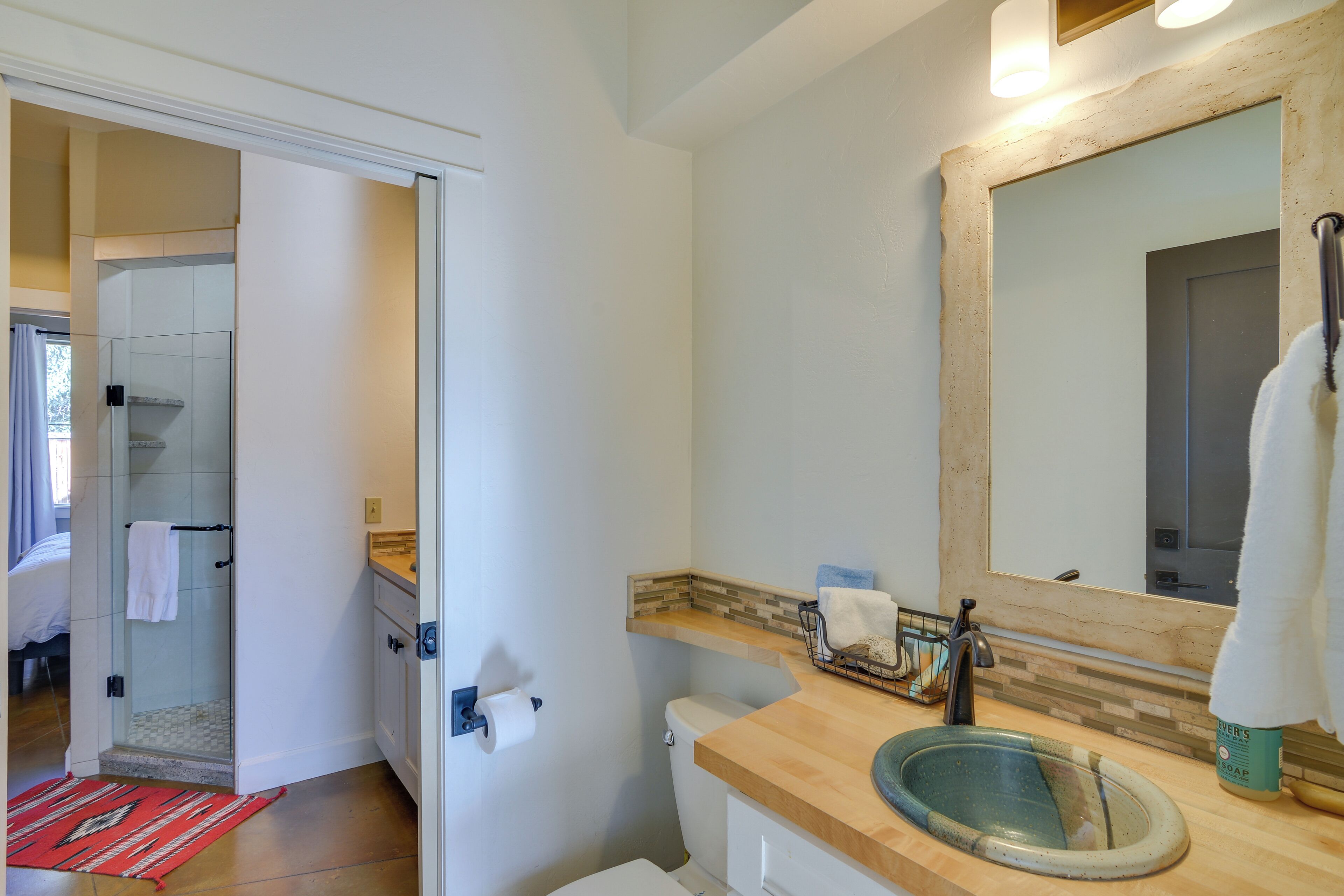 A bathroom with a glass shower, a wooden vanity, a sink, and a mirror.