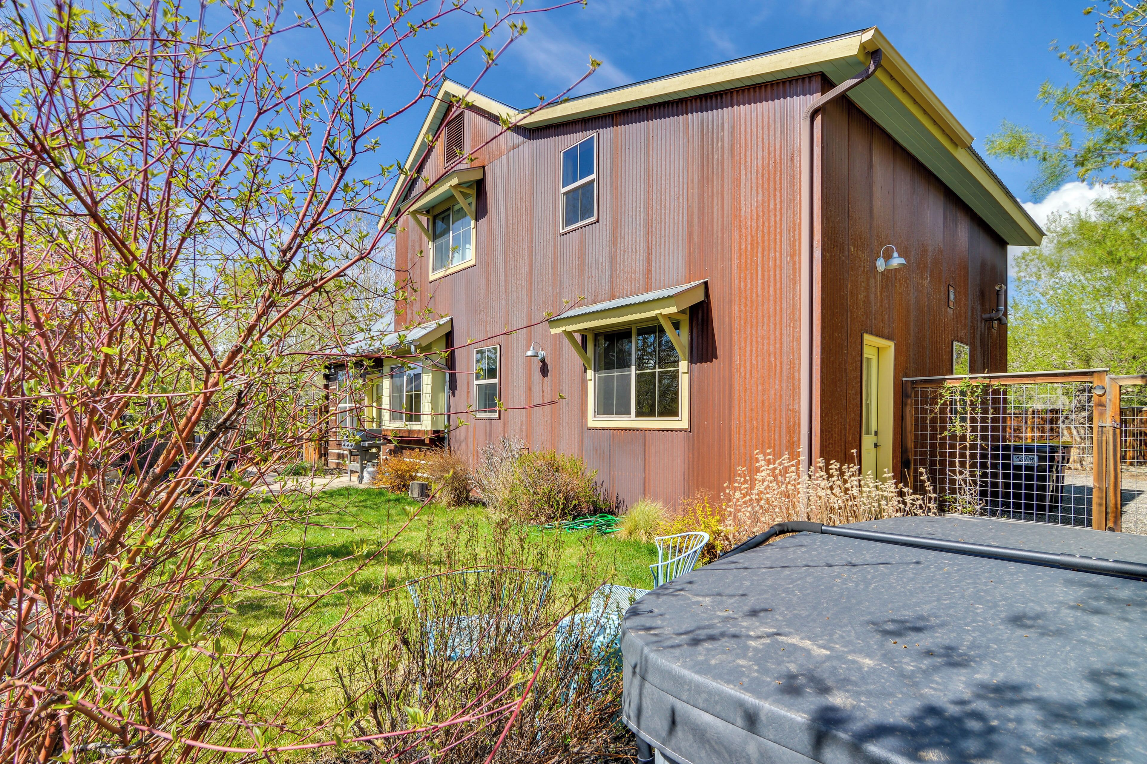 A two-story wooden house with a front porch, a fenced yard, and a green lawn.