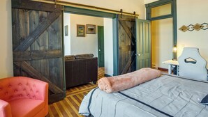 A bedroom with a bed, a pink chair, a wooden bench, and a sliding barn door. - Downtown Montrose Apartment, 12 Mi to Natl Park! (Montrose)