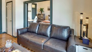 A living room with a dark brown leather sofa, a wooden coffee table, and a modern floor lamp. - Downtown Montrose Apartment, 12 Mi to Natl Park! (Montrose)