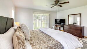 Ein Hotelzimmer mit Bett, Schreibtisch, Fernseher, Kommode und Deckenventilator.