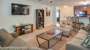 A living room with a flat-screen TV, a bookshelf, a coffee table, and a sofa.