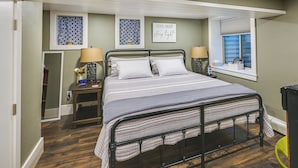 A bedroom with a bed, bedside lamps, a nightstand, a window with blinds, and two wall art pieces. - Laramie Gem < 1/2 Mi to University of Wyoming! (Laramie)