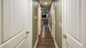 A hallway with white doors and a wooden floor leading to a kitchen area. - Laramie Gem < 1/2 Mi to University of Wyoming! (Laramie)