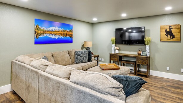 A living room with a large sectional sofa, a flat-screen TV mounted on the wall, and a wooden coffee table. - Laramie Gem < 1/2 Mi to University of Wyoming! (Laramie)
