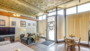 A spacious living area with a large TV, comfortable seating, and a dining table. - Cozy Abode in Historic Yankton - Heart of the City (Yankton)