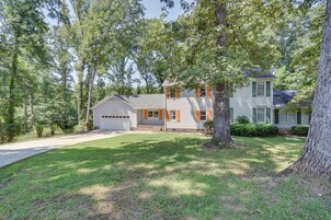 A two-story house with a garage, surrounded by trees and a well-maintained lawn.