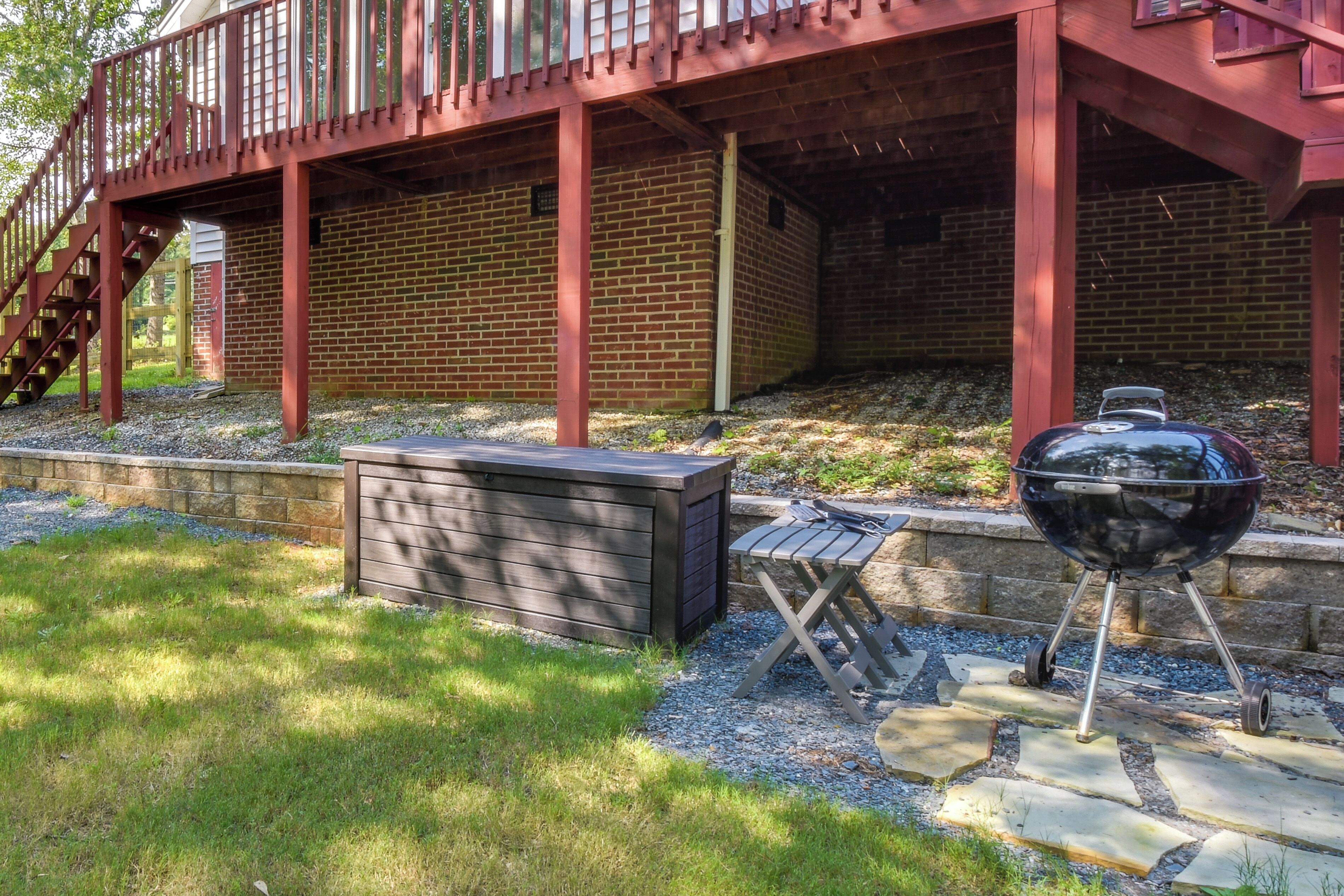 A covered outdoor area with a brick wall, a wooden deck, and a barbecue grill.