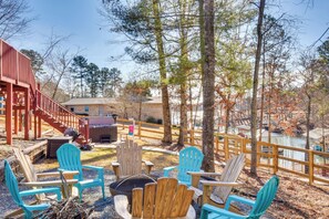 A deck with Adirondack chairs, a fire pit, and a wooden staircase leading to a building.