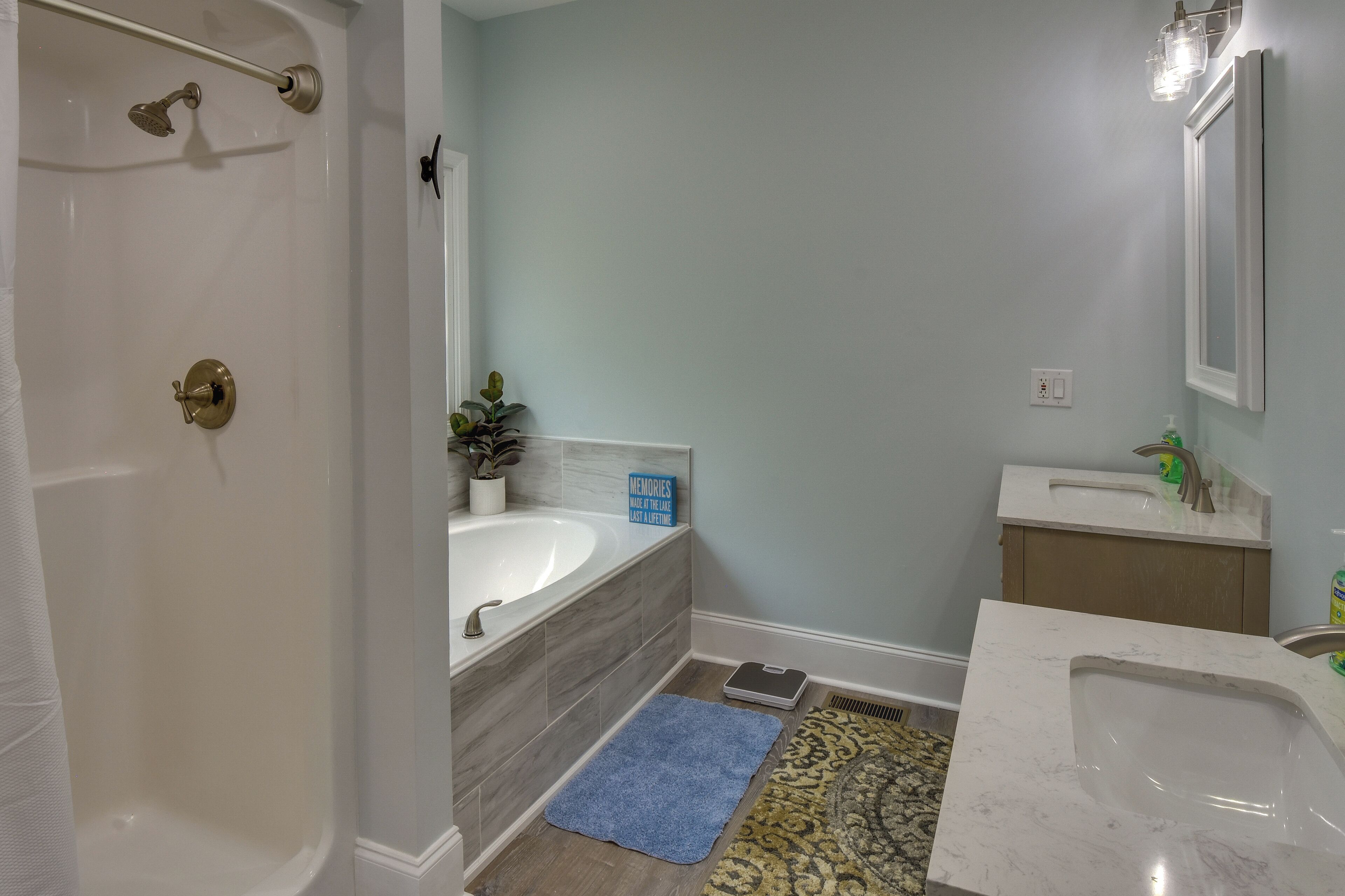 Une salle de bain avec une baignoire, un lavabo, un miroir et une douche.