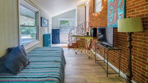 Una habitación acogedora con una cama, un televisor y una pared de ladrillo.