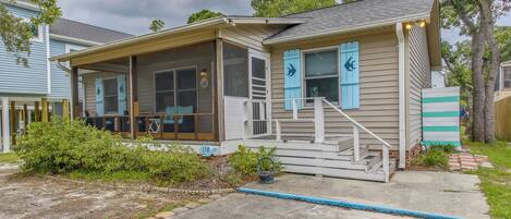 A house with a covered porch, a staircase, and a number '158' sign.