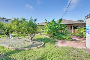 Um imóvel residencial com jardim, pátio e estrutura de casa visível.