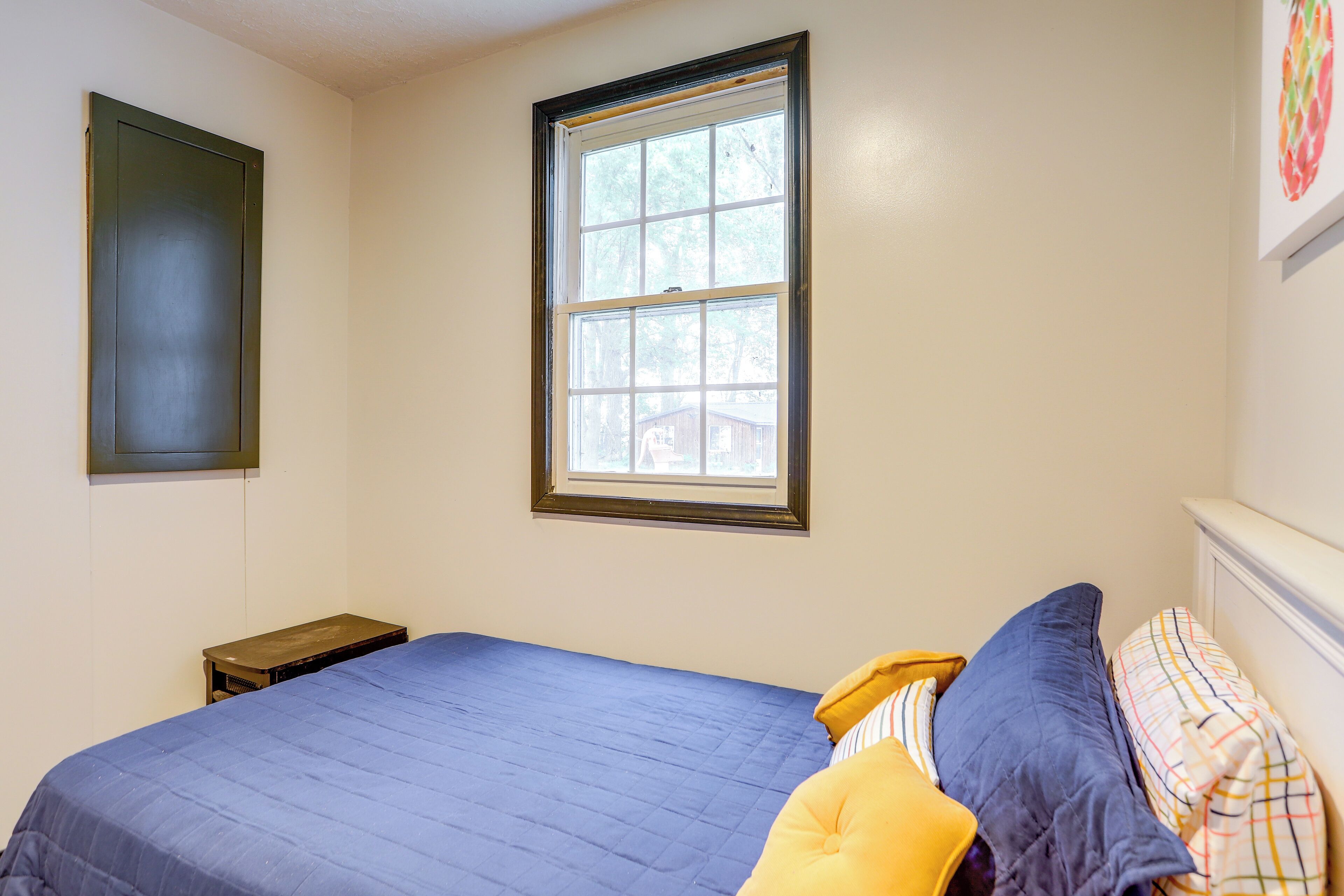 Quarto com uma cama de solteiro, uma janela e uma mesinha de cabeceira.