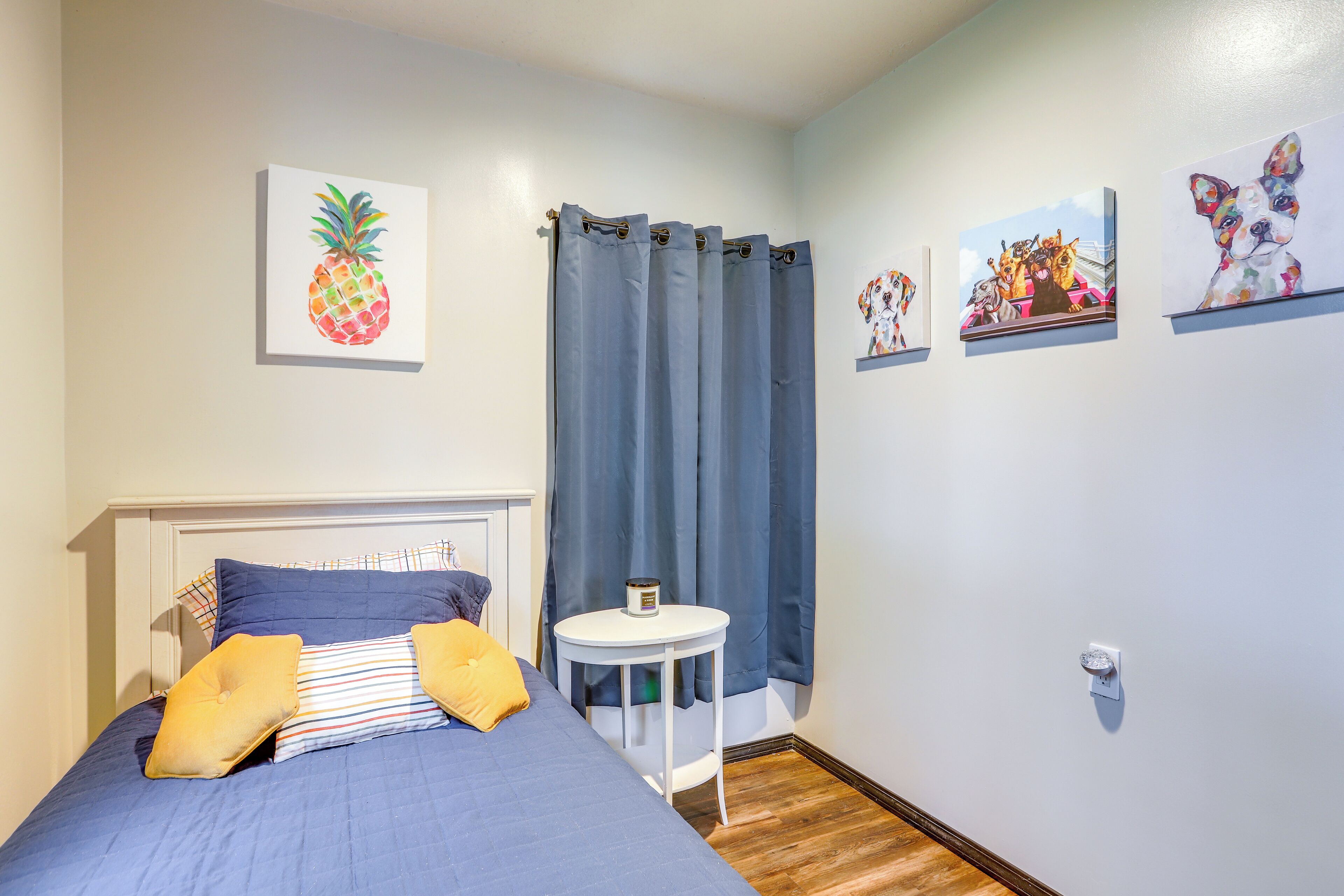 Ein Schlafzimmer mit einem Bett, einem kleinen runden Tisch und Kunstwerken an den Wänden.