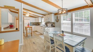 A kitchen with wooden beams, white cabinets, a dining table with chairs, and a view through the windows. - Bright Byrdstown Home w/ Views of Dale Hollow Lake (Byrdstown)