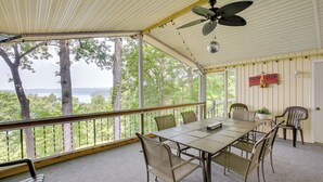 A covered outdoor area with a table and chairs, a ceiling fan, and a view of trees and water. - Bright Byrdstown Home w/ Views of Dale Hollow Lake (Byrdstown)