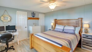 A bedroom with a wooden bed, a desk with a computer, a chair, a ceiling fan, and a wall-mounted sign. - Bright Byrdstown Home w/ Views of Dale Hollow Lake (Byrdstown)