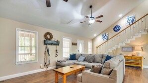 A spacious living room with hardwood floors, a sectional sofa, a wooden coffee table, and a staircase with a railing.