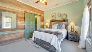 A bedroom with a bed, two bedside tables with lamps, a ceiling fan, and a green door. - Secluded Blanco Home w/ Private River Access! (Blanco)