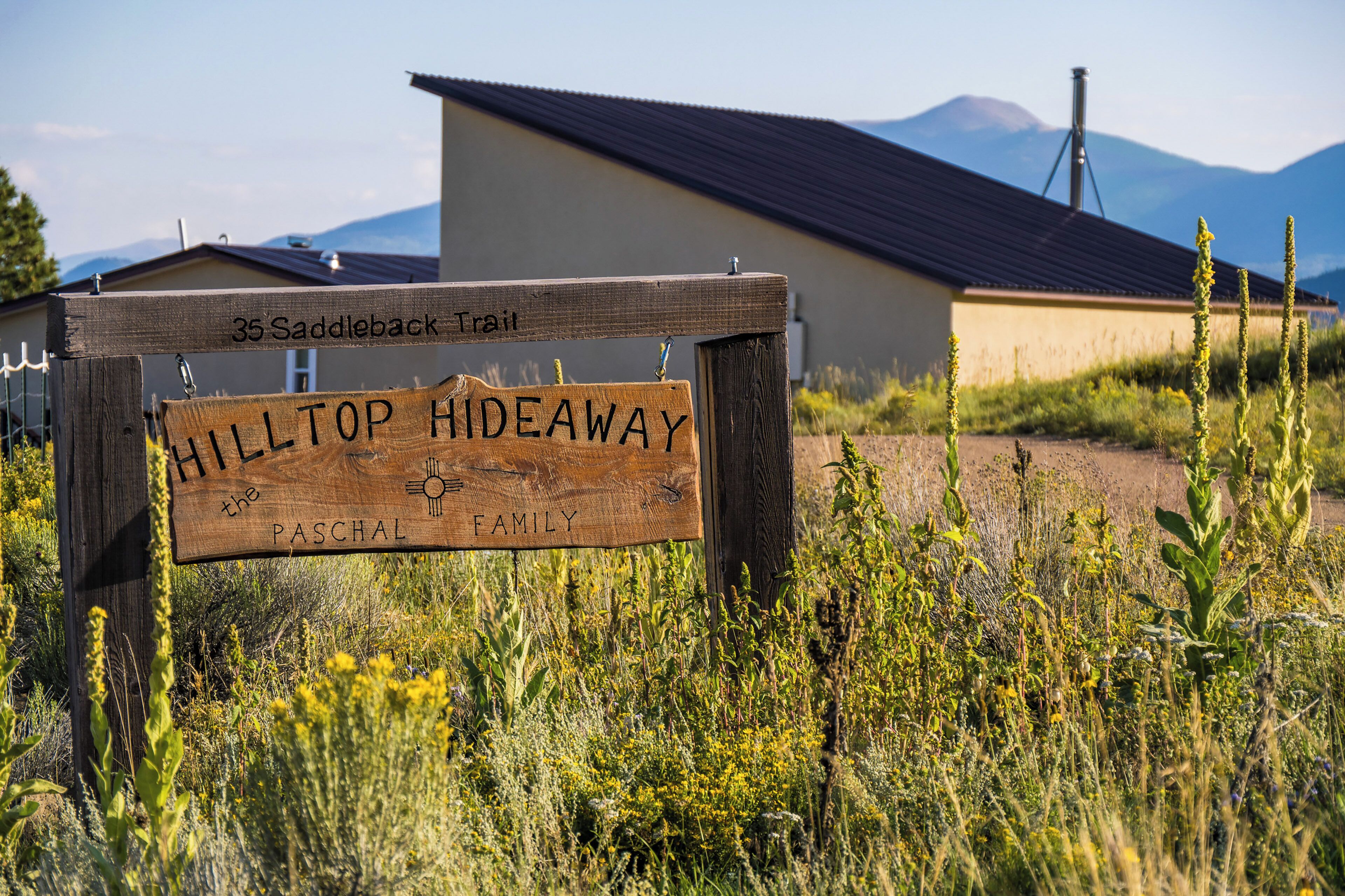 Segnaletica in legno per Hilltop Hideaway con montagne sullo sfondo.