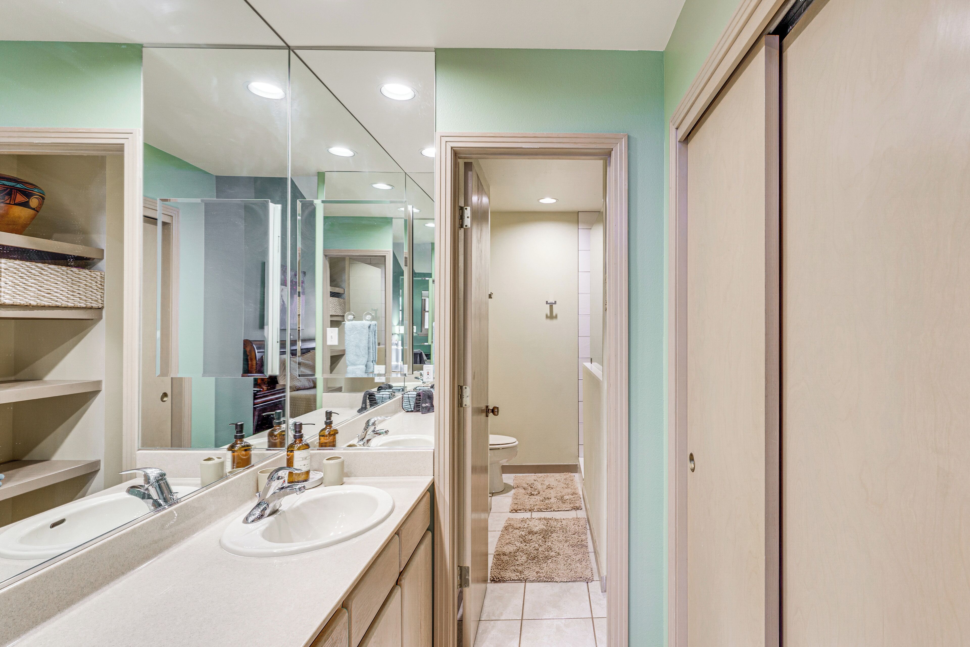 Un bagno moderno con due lavabi, uno specchio grande e una doccia a filo pavimento.