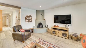 A modern living room with a fireplace, leather sofa, wooden entertainment unit, and a flat-screen TV. - Half Mi to Angel Fire Resort: Townhome w/ Grill! (Angel Fire)