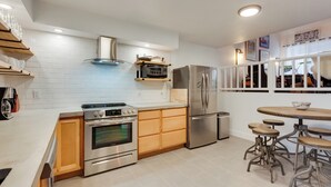 A modern kitchen with built-in appliances, wooden cabinets, and a bar area with stools. - Chic Angel Fire Condo: Walk to Ski Resort! (Angel Fire)