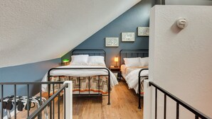 A dormitory room with two beds, a small table, and a nightstand. - Chic Angel Fire Condo: Walk to Ski Resort! (Angel Fire)