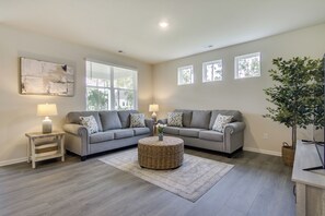 A living room with a grey sofa, two side tables, a round wicker coffee table, and a large plant. - 3 Mi to Bethany Beach: Ocean View Home w/ Patio (Ocean View)