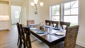 A dining area with a wooden table set for four, surrounded by wicker chairs. - Ocean View Home w/ Kayaks ~ 2 Mi to Bethany Beach (Ocean View)