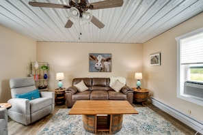 Relax in a cozy living room with a comfortable sofa, armchair, and coffee table, complemented by a unique artwork and patterned rug.