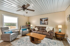 Relax in this inviting living room with a high ceiling, comfortable seating area, and a decorative cow painting.