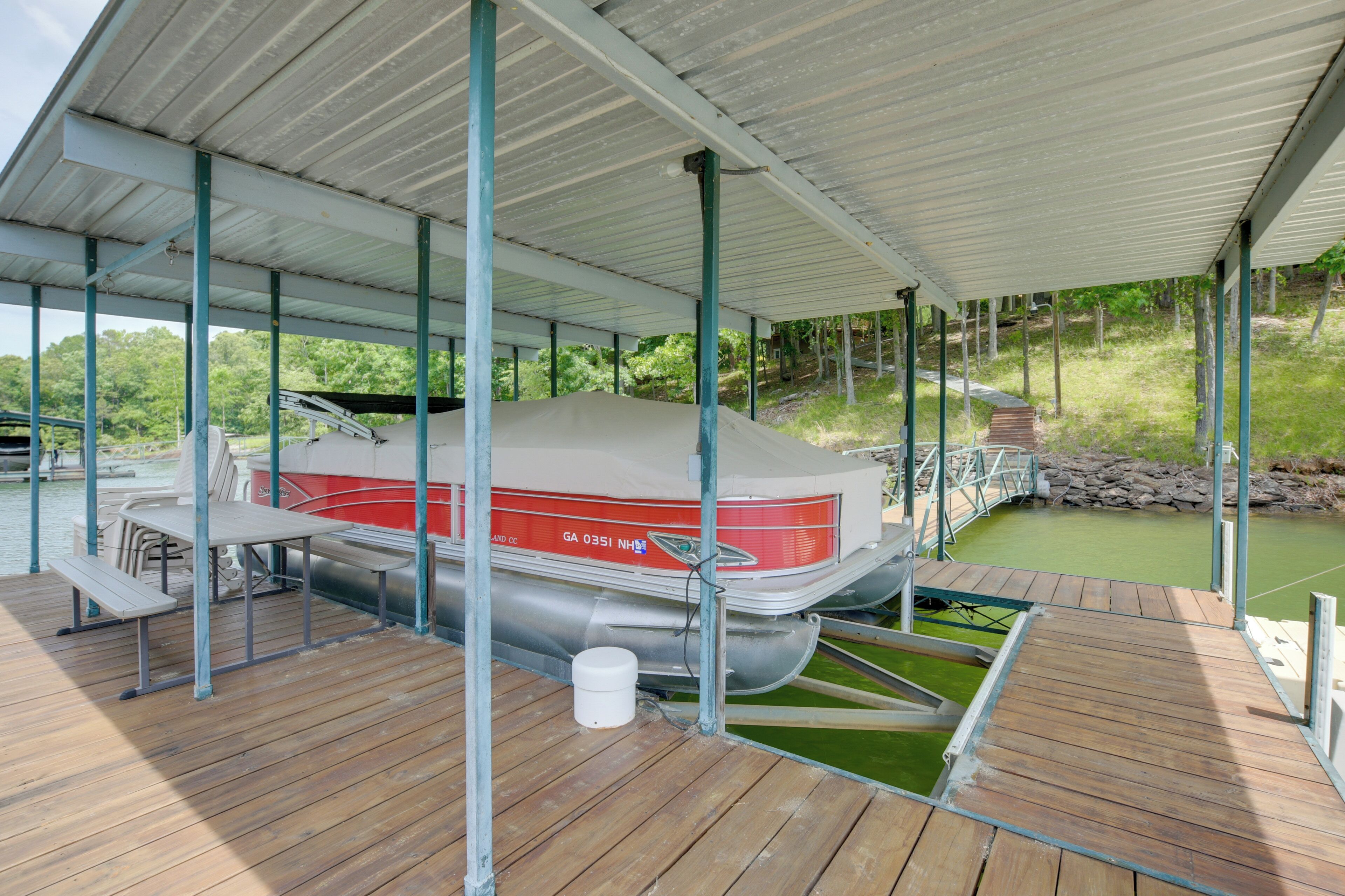 Un muelle cubierto para embarcaciones con una mesa de picnic y un barco llamado GA 0351 NH.