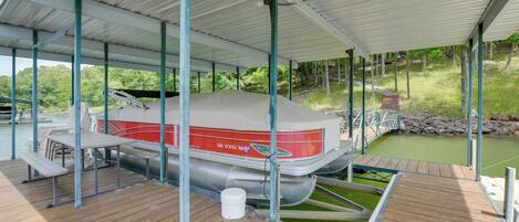 Un muelle cubierto para embarcaciones con una mesa de picnic y un barco llamado GA 0351 NH.