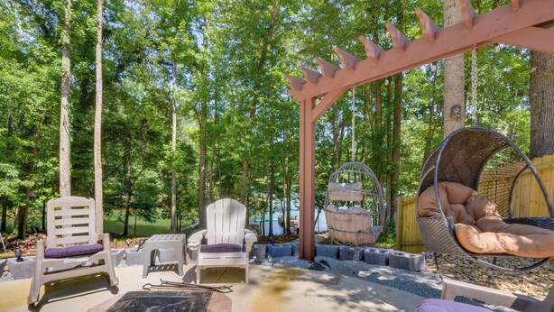 Un'area patio esterna con poltrone Adirondack, una sedia sospesa e un braciere.