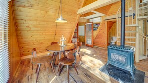 Un intérieur en bois avec une table ronde et des chaises, un poêle et un escalier.