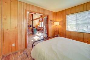 A wooden-paneled room with a bed, a desk, and a window with blinds. - Pet-friendly Arizona Cabin - Fire Pit, Near Skiing (Munds Park)