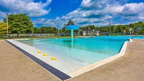 Une piscine dotée d’une structure de toit bleue, entourée d’une terrasse en béton et d’une clôture en métal.
