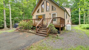 Une cabane à deux étages dotée d’une terrasse en bois, d’un porche couvert et d’une grande fenêtre.