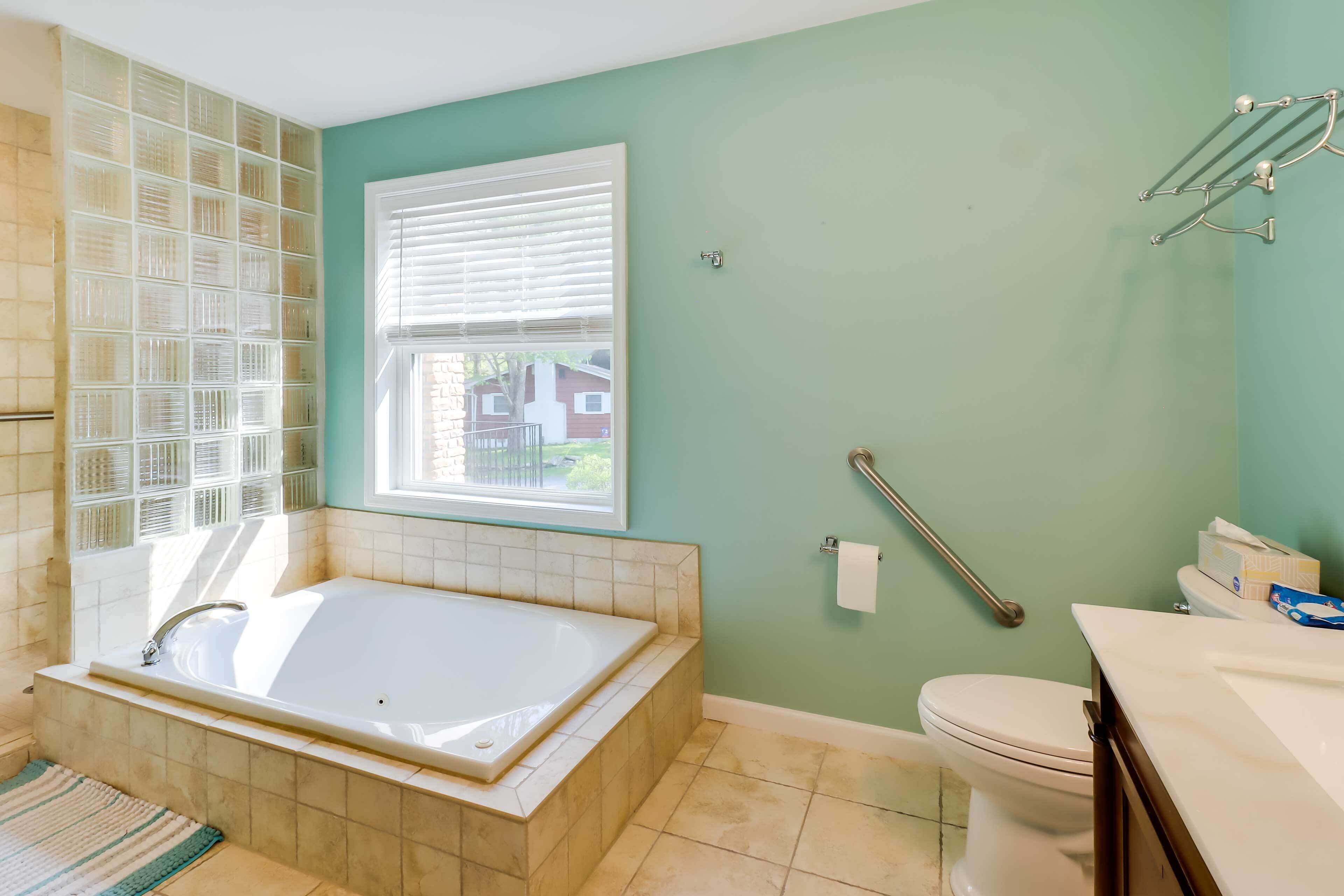 A bathroom with a bathtub, toilet, and window.