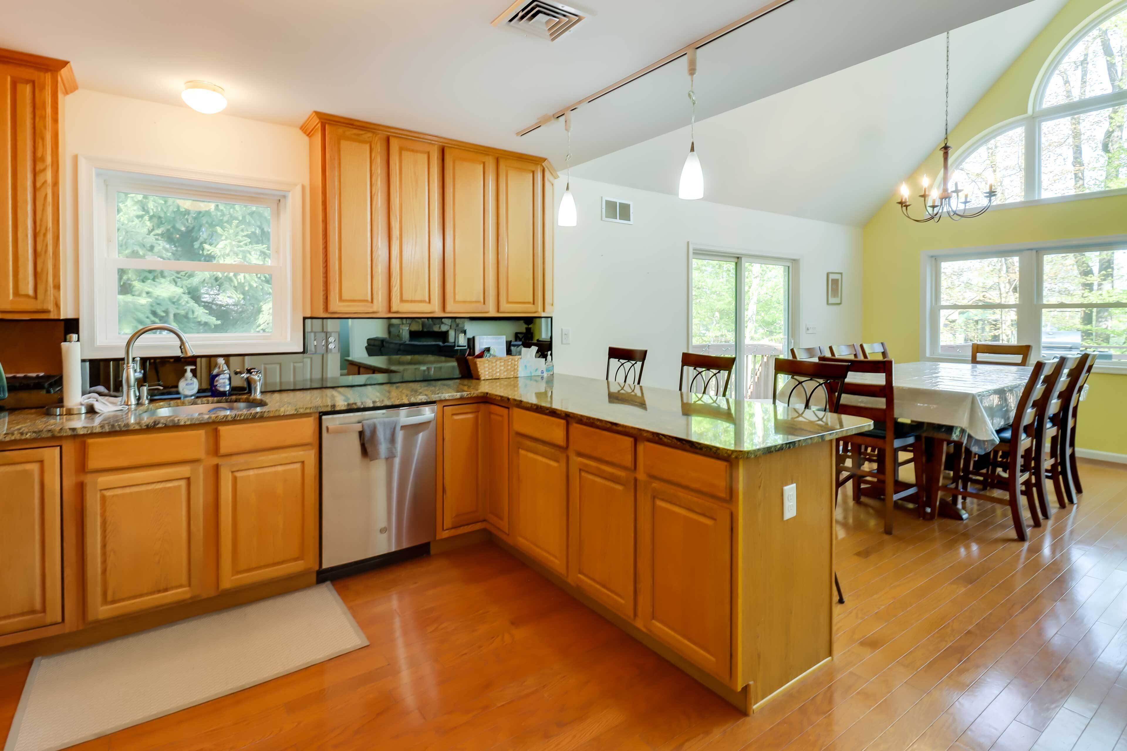 A spacious kitchen with wooden cabinets, a dishwasher, and a dining area with a table and chairs.